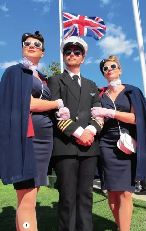  ?? ?? 1. Representi­ng aircrew of the era, Elise Donoghue, Rufus Cameron and Maddie Adams stand beneath a flag at half mast;
