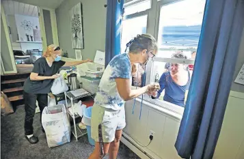  ?? [DORAL CHENOWETH/DISPATCH] ?? Volunteer Suzette Viola serves coffee to Shena Snodgrass through the window at the Helping Other People Excel office on Sullivant Avenue. Behind Viola is volunteer Cindy Denney. HOPE offers food, clothing, personal items and access to rehabilita­tion. Because of COVID-19 restrictio­ns, the staff began walk-up window service instead of having people enter the building. Staffers say the system has worked out well.