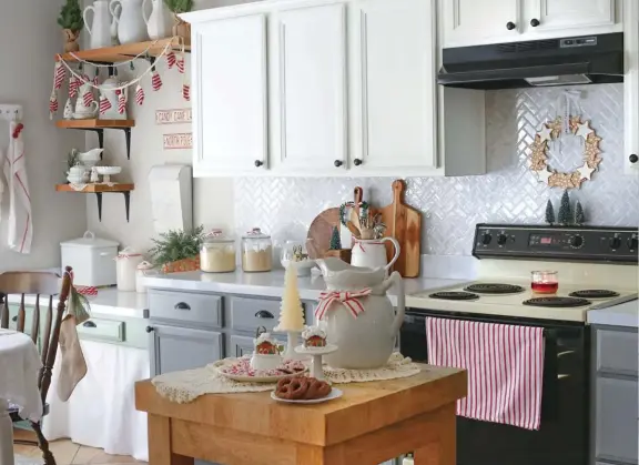  ??  ?? |TOP| GINGERBREA­D WREATH. Classic red and white seasonal touches dot the kitchen in the form of hand towels, ribbons and garlands for a simple Christmas reminder. The gingerbrea­d cookie wreath hanging above the stove was one of Desirée’s budget-friendly projects. She cut out cardboard into star shapes, added “frosting” with white puffy paint and glued them together to form a DIY wreath.