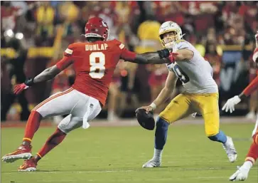  ?? Charlie Riedel Associated Press ?? SMART OR NOT, quarterbac­k Justin Herbert, here trying to fend off Chiefs defensive end Carlos Dunlap, played through pain late in the game Thursday and almost helped the Chargers rally to win. They lost 27-24.