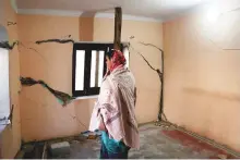  ?? ANI ?? A resident named Bindu looks at the cracks that appeared on her house prior to leaving as it has been marked unsafe by the district administra­tion due to the land subsidence.