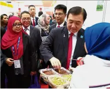  ??  ?? Ong trying a biscuit with chocolate dipping while touring the Malaysia Pavilion at the 14th China-Asean Expo in Nanning, China. Tasty treat: