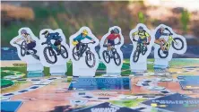  ??  ?? The board game “SEND IT!” features six mountain bike rider characters that players can choose to be.