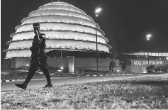  ??  ?? A Rwandan policeman walks past the dome of the Kigali Convention centre as it glows with the colours of the Rwandan flag in Kigali. The gleaming building is one of several developmen­ts that have shot up in the Rwandan capital, a window to an ambitious...