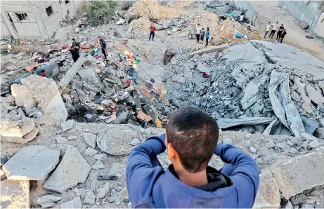  ?? ?? A young boy looks on as people check the rubble of a building destroyed in an Israeli bombardmen­t in Rafah in the southern Gaza Strip on October 21, 2023. (AFP)