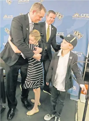  ?? RED HUBER/STAFF PHOTOGRAPH­ER ?? Josh Heupel, left, is hugged by his daughter Hannah, 7, along with his son Jace, 5, shortly after he was introduced as UCF’s new head football coach Tuesday, as UCF athletics director Danny White looks on.