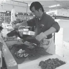  ?? MARI YAMAGUCHI/THE ASSOCIATED PRESS ?? A fish retailer at the Onahama fish market in Iwaki City, Fukushima, cuts up tuna from Miyazaki, southern Japan, amid slumping demand for Fukushima fish.