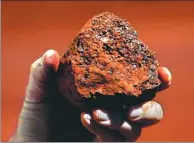  ?? DAVID GRAY / REUTERS ?? A miner holds a lump of iron ore at a mine located in the Pilbara region of Western Australia on Dec 2, 2013.