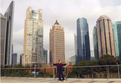  ??  ?? Šanghajska panorama z moškim, ki vadi tai chi. Ljudje, ki telovadijo, plešejo ali pojejo, niso na Kitajskem prav nič sramežljiv­i.