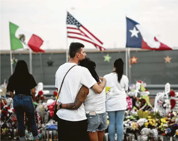  ?? Sandy Huffaker / Getty Images ?? People gather at a makeshift memorial on Aug. 15, 2019, outside a Walmart in El Paso, where a mass shooting 12 days before resulted in the deaths of 23 people.