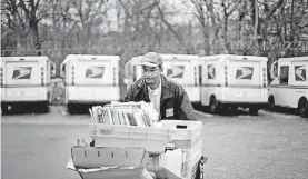  ?? [AP FILE PHOTO] ?? A U.S. Postal Service letter carrier gathers mail to load into his truck before making his delivery run in the East Atlanta neighborho­od in Atlanta. The U.S. Postal Service wants to boost its business this holiday season by offering cheap next-day...