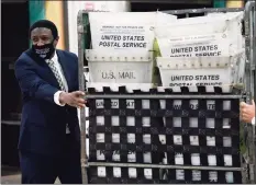  ?? Lynne Sladky / Associated Press ?? Broward County Mayor Dale V.C. Holness helps load vote-by-mail ballots into a truck for transport to a local U.S. Postal Service office at the Broward Supervisor of Elections Office, Thursday in Lauderhill, Fla. Vote-by-mail ballots will begin going out to residents in Broward County Thursday.