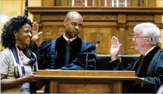  ??  ?? Retired Georgia Supreme Court Chief Justice P. Harris Hines (right) swears in presiding Georgia Supreme Court Justice Harold D. Melton (center) as the new court Chief Justice during the swearing-in ceremony on Thursday. Harold’s wife, Kimberly Melton, held the Bible while he was sworn in.