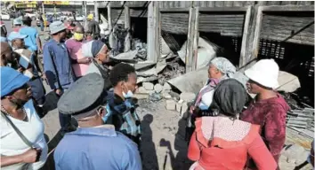  ?? /ANTONIO MUCHAVE ?? On-lookers and owners of the stalls that were burned down by unknown people in Alexandra on Wednesday night.