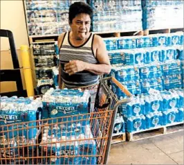  ?? TASSANEE VEJPONGSA/AP ?? A resident stocks up on bottles of water Saturday at a home supply store in Guam. The country is coping with North Korea’s threat to launch missiles at the Pacific island.