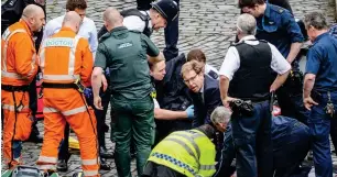  ?? AP ?? LEGISLATIV­E ACTION: Conservati­ve Member of Parliament Tobias Ellwood, centre, helps emergency services attend to an injured person outside the Houses of Parliament in London on Wednesday. —