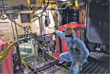  ?? KO SASAKI/THE NEW YORK TIMES ?? Daisuke Hirose is shown in June in the undamaged Unit 5 reactor at the Fukushima Daiichi Nuclear Power Plant, in Fukushima, Japan. The Japanese government and companies used radiation-hardened machines to search for the fuel that escaped the Fukushima...