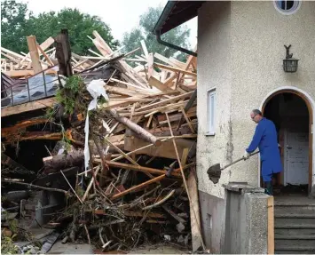  ?? Foto: Christof Stache/BJV, dpa ?? 3. Juni 2016: Ein Anwohner schippt Schlamm aus seinem Haus – direkt vor einen riesigen Trümmerber­g, der sich im Garten auf getürmt hat. Diese Aufnahme war eines der Siegerfoto­s beim Wettbewerb Pressefoto Bayern 2016.