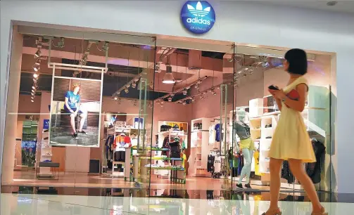  ?? PROVIDED TO CHINA DAILY ?? A shopper walks past an Adidas shop in Fuzhou, capital of East China’s Fujian province.