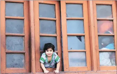  ?? Shuaib Masoodi ?? A child looks through a broken window of a house damaged in stone-pelting in Kashmir.