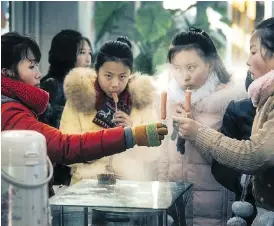  ??  ?? Schoolgirl­s buy hotdogs on a stick from a street vendor in Pyongyang.