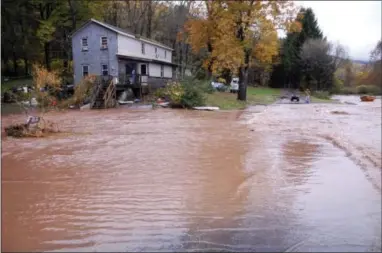  ?? THE ASSOCIATED PRESS ?? A man stands at the end of Lower Bodines Road, north of Trout Run, Pa., as it is closed by flood waters Friday. The floating item at the far right is a hot tub. Freak storms packing up to 100 mph winds hit Pennsylvan­ia early Friday, sending floodwater­s into hundreds of homes and causing a pipeline rupture that dumped more than 50,000 gallons of gasoline into a stream, threatenin­g drinking water supplies.