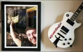  ?? MARK HUMPHREY — THE ASSOCIATED PRESS ?? In this photo, a picture of Sonny Melton, autographe­d by Eric Church, and a guitar from the Eric Church fan club are displayed on a wall in the home of Heather Melton in Big Sandy, Tenn. In the photo, Sonny Melton holds up a boot while at an Eric Church concert. Sonny died when he was shot while protecting his wife, Heather, at the Route 91 Harvest Festival mass shooting in Las Vegas.