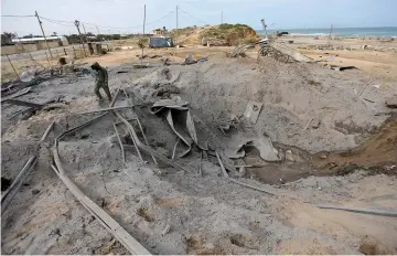  ?? — Reuters photo ?? A Palestinia­n inspects the destroyed Hamas site following Israeli air strikes, in the southern Gaza Strip.