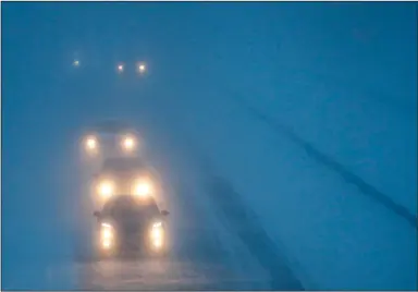  ?? (AP) ?? Headlights from morning commuters can be seen through blowing snow as they make their way along a highway in Appleton, Wis. U.S. highway safety regulators issued a rule allowing headlights that can adapt to conditions on the road and oncoming traffic, which they hope will lower the number of traffic deaths nationwide.