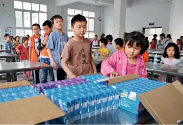  ??  ?? Le 10 juin 2020, à l’école primaire Peng Yongwu dans le district de Yunyang, à Chongqing, des enfants « laissés derrière » font la queue à la cafétéria de l’école pour recevoir une ration supplément­aire de lait.