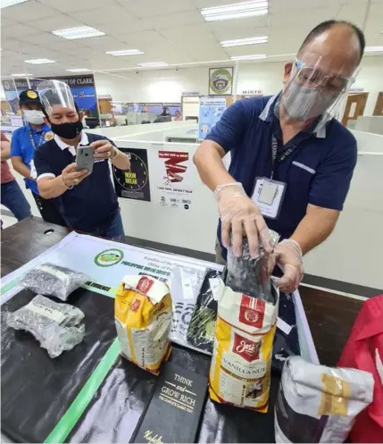  ?? - Chris Navarro ?? HIGH GRADE MARIJUANA
Agents of Bureau of Customs Port of Clark examine sP1.1 million worth of high grade marijuana placed inside coffee bean packs.