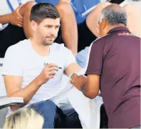  ??  ?? NOT TOU BUSY Gerrard gives a fan his autograph yesterday