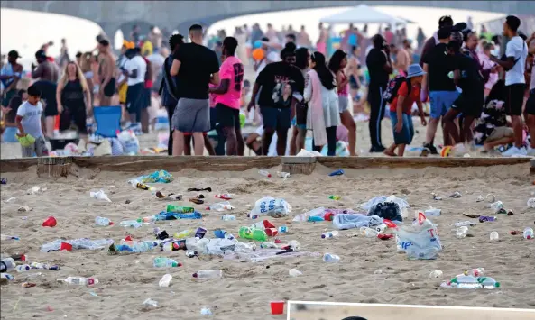  ??  ?? Eyesore by the sea: Beach is strewn with rubbish as revellers party