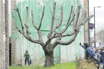  ?? JONATHAN BRADY/PA VIA AP ?? People check out a mural that appeared overnight on a residentia­l building in Finsbury Park, which has been confirmed to be by graffiti artist Banksy, in London on Monday.