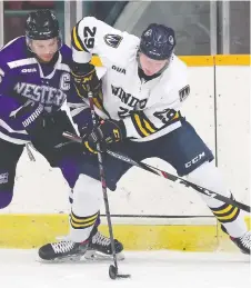  ?? DAN JANISSE ?? Ryan Bechtel of Western and Trent Fox of Windsor battle for the puck during a game on Friday at the Capri Pizza Complex.