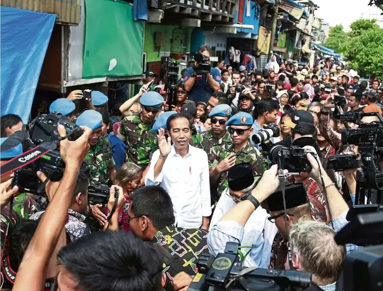  ?? — AP ?? Back in charge: Joko waving to reporters as he leaves after declaring his victory in the country’s presidenti­al election at a slum in Jakarta.