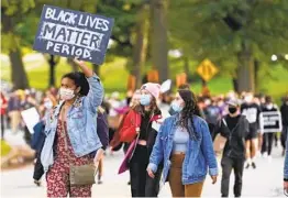  ?? TONY DEJAK AP ?? A woman holds up a sign during a protest Tuesday in Cleveland. Racism trips up Black police candidates at the beginning of the applicatio­n process experts say.