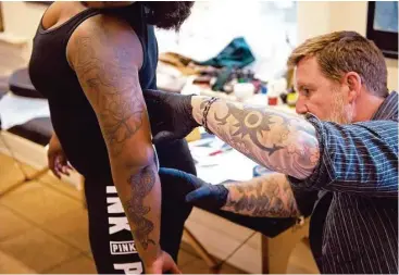  ?? Brendan Smialowski / AFP/Getty Images ?? Butch Johnson, owner of Champion Tattoo Company, transfers a tattoo sketch to the arm of U.S. Navy Corpsman Taylor Hoyte recently in Washington, D.C. The Navy has decided to loosen its rules about tattoos in hopes of turning away fewer desired recruits.