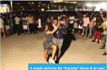  ??  ?? A couple performs the “Kizomba” dance at an open space in Luanda, as people watch them.