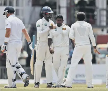  ??  ?? SPIN KING ...Sri Lankan bowler Rangana Herath, second right, celebrates the dismissal of England’s batsman Ian Bell, left, during the fourth day of the first Test in Galle, spinner Herath ending the game with superb figures of 12-171