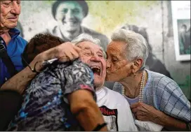  ?? PHOTOS BY ANTONIO CALANNI/ASSOCIATED PRESS ?? Martin Adler (center) receives a kiss Monday from Mafalda (right) and Giuliana Naldi, who he is credited with saving during World War II, at Bologna’s airport, Italy. The 97-year-old U.S. veteran met the three siblings — now octogenari­ans themselves — in person, eight months after a video reunion.