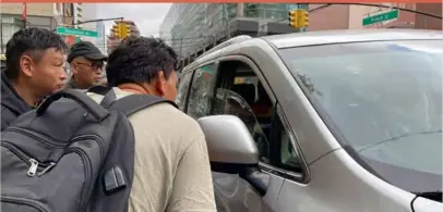  ?? ?? Wang Gang, 36, front, a Chinese immigrant, talks with the driver of a car with others as they try to get a daily paid job working constructi­on or in another trade in the Flushing neighborho­od of the Queens borough of New York