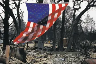  ?? Leah Millis / The Chronicle ?? A firefighte­r works in one of several neighborho­ods in Santa Rosa that were reduceed to ash as an American flag flies from the remains of a home on Willowview Court off Skyview Drive.
