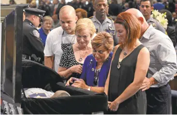  ?? PATRICK DENNIS-POOL/GETTY IMAGES ?? The family of slain police Officer Matthew Gerald, including his widow, Dechia Gerald, right, visit the casket of police Cpl. Montrell Jackson during Jackson’s funeral at the Living Faith Christian Center on Monday in Baton Rouge, Louisiana.