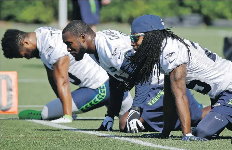  ?? — AP PHOTO ?? Seahawks cornerback Richard Sherman, right, stretches with strong safety Kam Chancellor, centre, and free safety Earl Thomas at Day 1 of training camp Sunday in Renton, Wash.