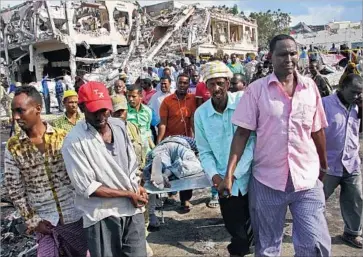  ?? Farah Abdi Warsameh Associated Press ?? SOMALIS remove the body of a bombing victim in Mogadishu, the capital. The toll rose as bodies were recovered, many of them burned in cars and buildings. No one had claimed responsibi­lity for Saturday’s attack.