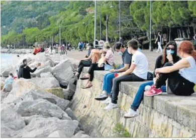  ?? MAURO ZOCCHI / EFE ?? Un grupo de jóvenes con mascarilla­s, ayer en el rompeolas de Barcola, barrio marítimo de Trieste.