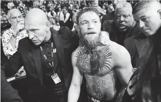  ?? JOHN LOCHER THE ASSOCIATED PRESS ?? Conor McGregor is escorted from the cage area after fighting Khabib Nurmagomed­ov in a lightweigh­t title mixed martial arts bout at UFC 229 in Las Vegas on Saturday. Nurmagomed­ov won the fight by submission during the fourth round to retain the title.