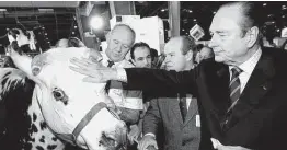  ?? Associated Press file photo ?? French President Jacques Chirac pets a cow while eating a piece of cheese as he inaugurate­s the 35th Agricultur­e Fair in Paris on March 1, 1998.