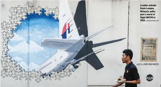  ?? JOSHUA PAUL/AP ?? A waiter outside Kuala Lumpur, Malaysia, walks past a mural of flight MH370 in 2016.